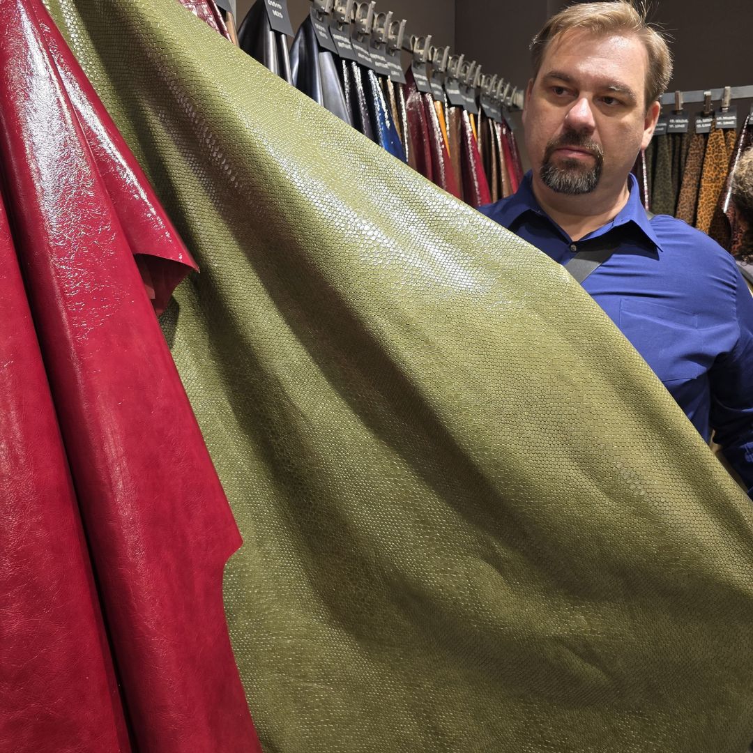 Man examining premium Italian leather materials at Milan trade show for Cappello Fashion’s upcoming handbag and hat collections.