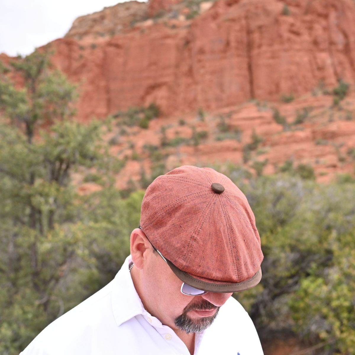 man in Rustico Linen Newsboy Hat with leather  button and visor with sodona red rocks background 