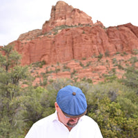 man in Blue Genova Linen Newsboy Hat with brown visor with sedona red rocks in background