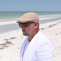 Guy in Taupe Rapallo Linen Flat Cap on the beach.  Summer Cap 