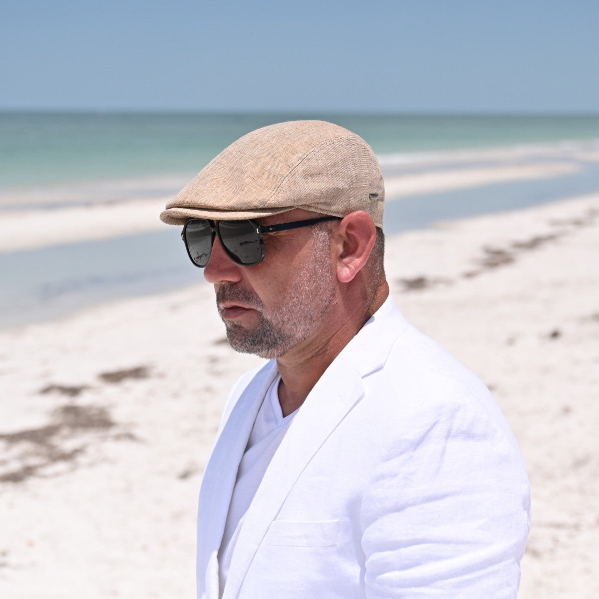 Guy in Taupe Rapallo Linen Flat Cap on the beach.  Summer Cap 