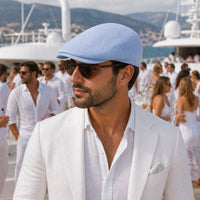 blue Palermo Linen Cap – Italian Flat Cap, Unisex on the guy with other people in background on the yacht