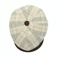Beige Bartolomeo linen cotton newsboy hat with plaid pattern and leather visor on white background