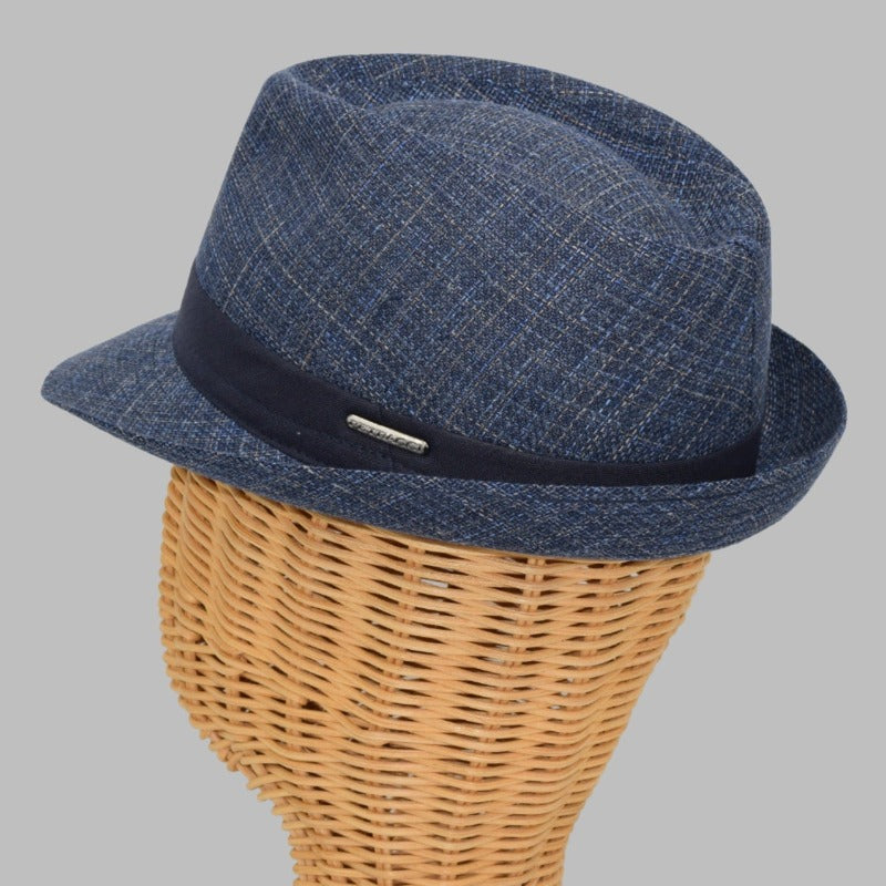 This image features a stylish Alpine fantasy hat made from a light, textured fabric with a blue band around the crown. It has a classic shape, with a slightly curved brim and a subtle logo on the side. The hat's neutral color and sophisticated design make it suitable for a variety of occasions.