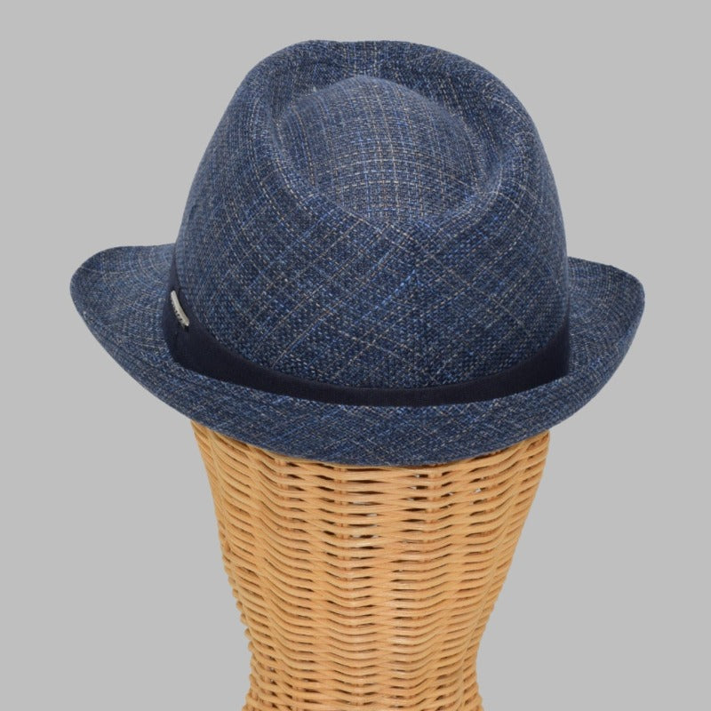 This image features a stylish Alpine fantasy hat on mannequin, made from a light, textured fabric with a blue band around the crown. It has a classic shape, with a slightly curved brim and a subtle logo on the side. The hat's neutral color and sophisticated design make it suitable for a variety of occasions.