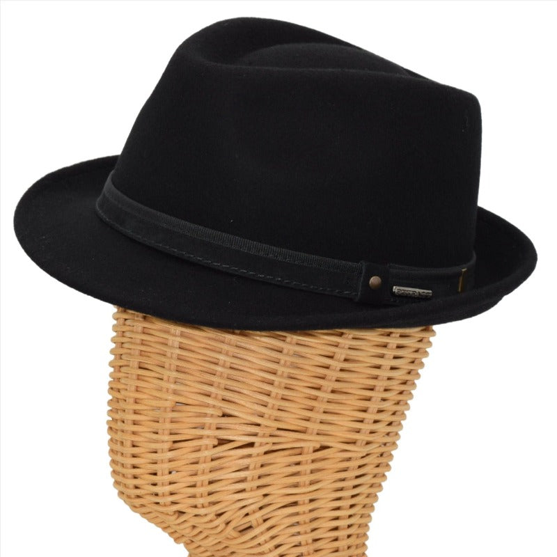 Side view of a black alpine hat displayed on a wicker mannequin head, featuring a black leather band with metallic accents for a sophisticated touch.