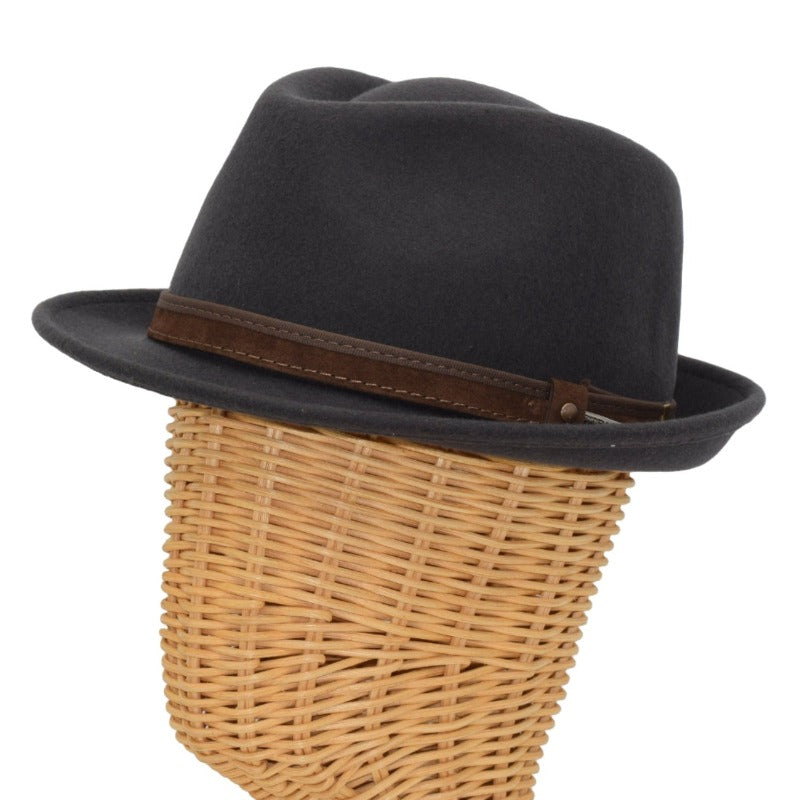 Side view of a grey alpine hat displayed on a wicker mannequin head, featuring a brown leather band with metallic accents for a sophisticated touch.