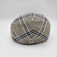 A beige flat cap with a blue plaid pattern, viewed from the back, showcasing the symmetrical stitching and classic design.