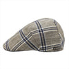 A beige flat cap with a classic blue plaid pattern, showcasing a side profile view and a subtle metallic logo accent on the side.