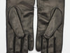 Back view of a pair of black gloves made from smooth leather, showcasing a sleek and minimalist design with a soft finish.