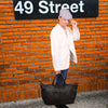 Person holding Amalfi Leather Black Bag on orange background