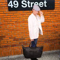 Person holding Amalfi Leather Black Bag on orange background