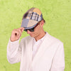 Person wearing a patchwork cap and sunglasses against a green textured background