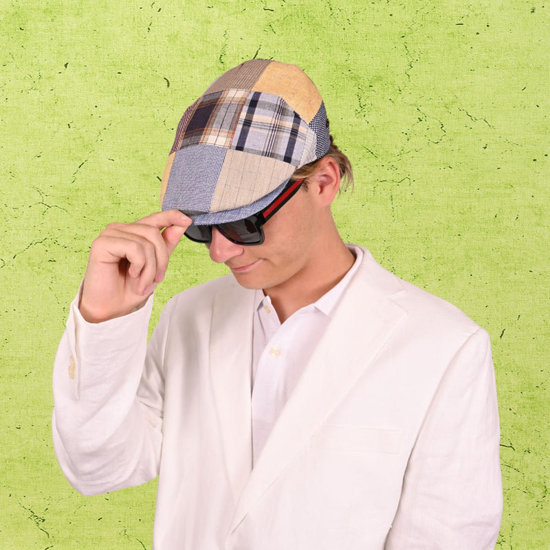 Person wearing a patchwork cap and sunglasses against a green textured background
