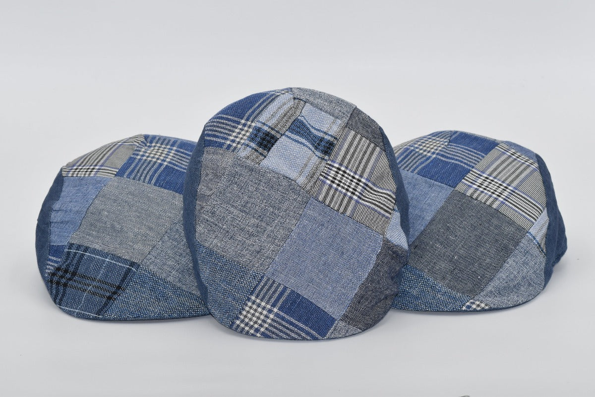 A set of three denim patchwork caps displayed side by side, showcasing their unique blend of blue fabrics with varying patterns, including plaid, herringbone, and solid weaves. Each cap highlights individual craftsmanship with a cohesive design theme, emphasizing style and versatility. Perfect for a modern yet classic look.