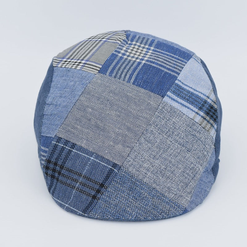 A detailed view of a classic ivy cap featuring a patchwork design made from assorted denim fabrics in varying shades of blue. The patterns include herringbone, plaid, and plain weaves, giving the cap a unique and textured appearance. The cap has a rounded top and a smooth, seamless finish.