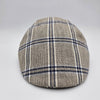 A beige flat cap with a blue plaid pattern, viewed from the front, highlighting its classic and timeless design.