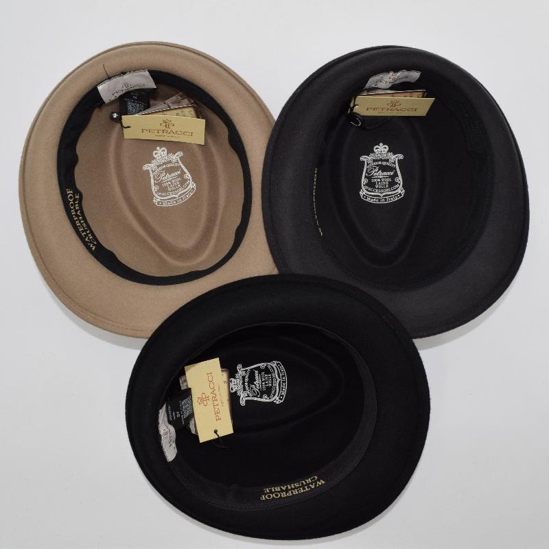 Top view of three alpine hats in beige, brown, and black, showcasing their inner linings with detailed branding and labels, highlighting craftsmanship and quality