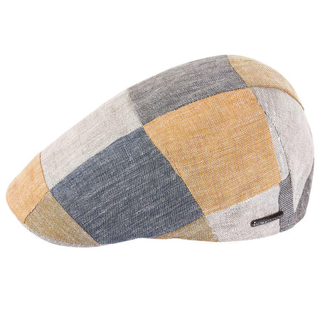 A colorful linen patchwork flat cap featuring panels in shades of blue, yellow, beige, and gray, with a subtle metallic logo accent on the side.