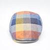 Front view of a colorful patchwork flat cap made from 100% linen. The cap showcases a vibrant mix of colors, including blue, yellow, orange, and red, with a subtle herringbone texture visible in the fabric.