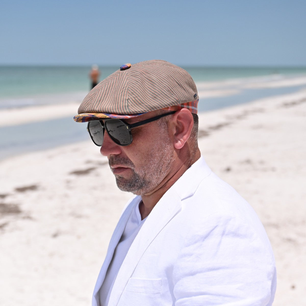 man in Multicolor Mantova Striped Newsboy Hat with beach in background