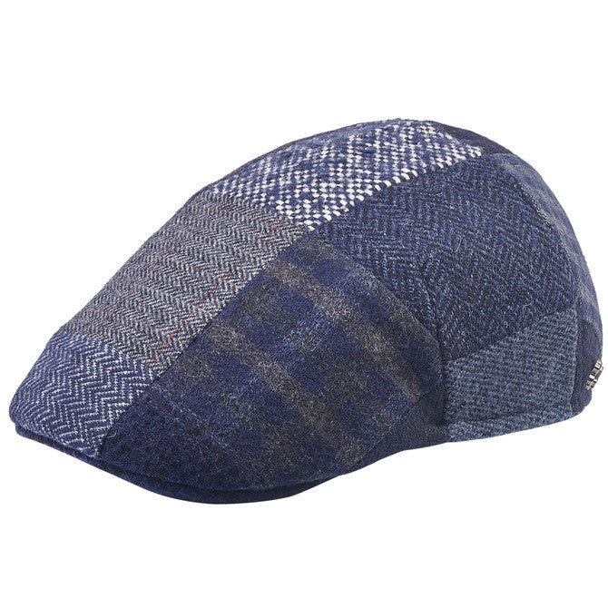 Side profile of a blue patchwork flat cap made of various textured fabrics, including herringbone, plaid, and tweed patterns. The cap features intricate stitching and a sleek, tailored design.