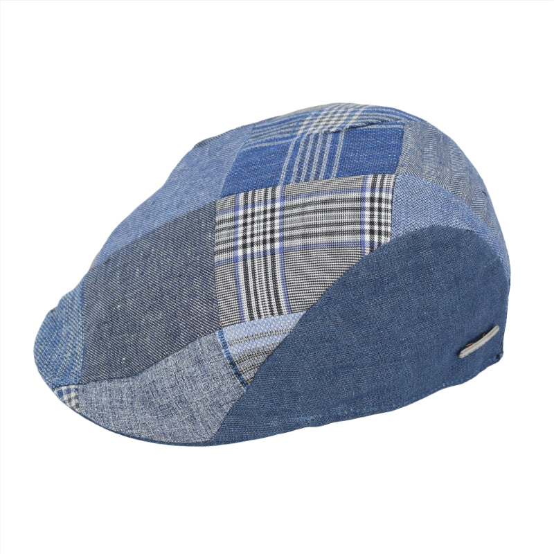 A stylish patchwork flat cap made from various shades and patterns of blue denim fabric, featuring a mix of solid, checkered, and plaid designs. The cap has a curved brim and a sleek, modern profile, with a small metallic logo detail on the side.