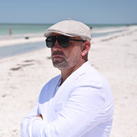 man in beige Prince of Wales Linen Newsboy Hat on the beach
