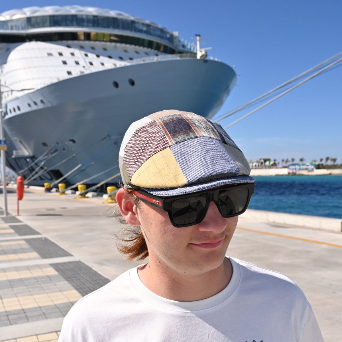 Multicolor Coppola Sports Fantasy Patchwork Cap on model with cruise ship in background