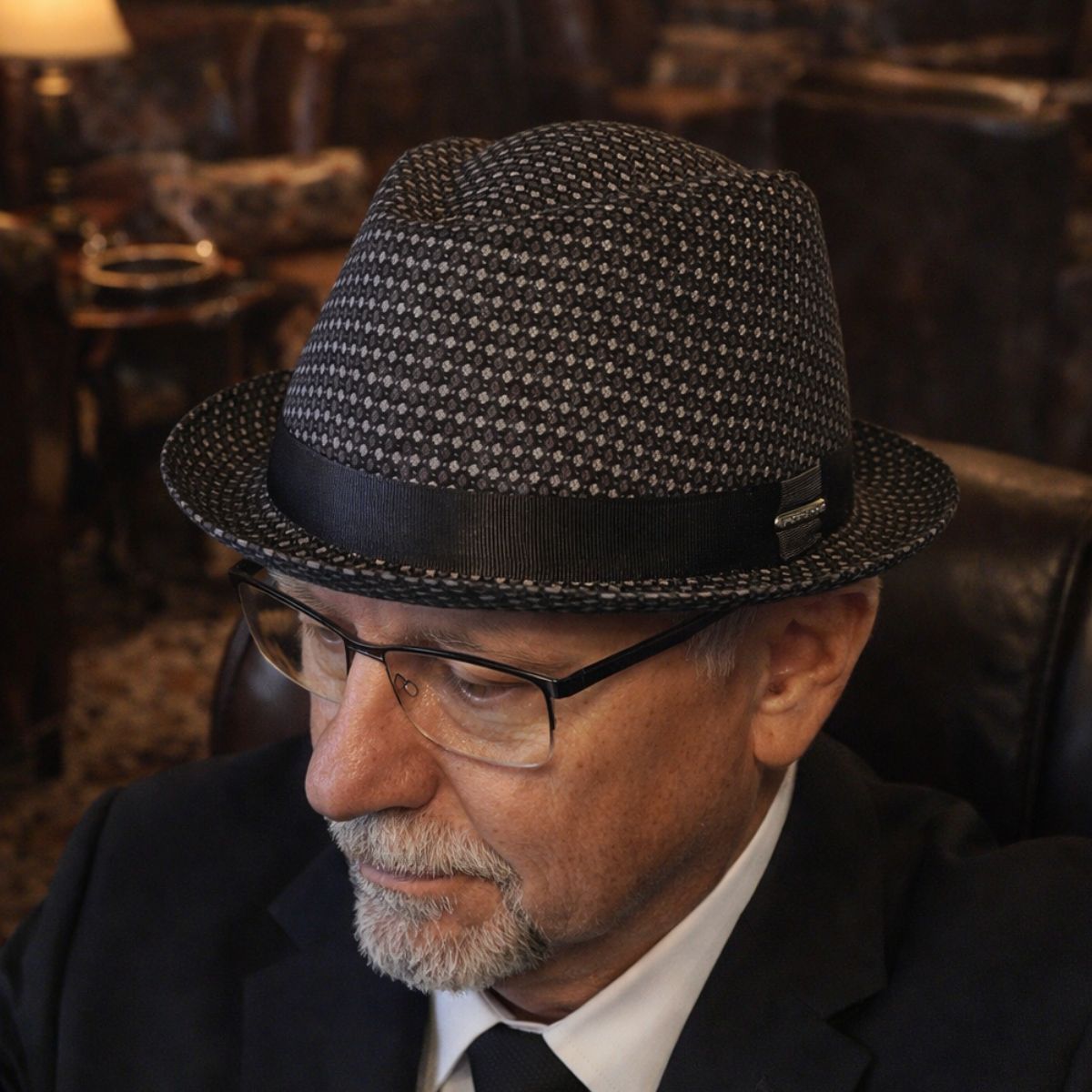 Gentleman in Black Royale Pork Pie Hat sitting on leather chair 
