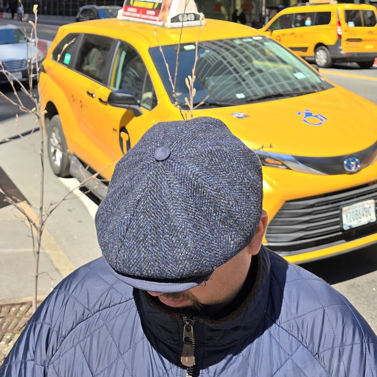 Guy in Navy Liguria Peaky Style Italian Hat with yellow cab in background