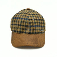 Bolzano Heritage Wool Baseball Cap featuring a brown and navy blue plaid pattern on the crown, with a textured brown visor and a small metal brand tag on the side, set against a plain white background.