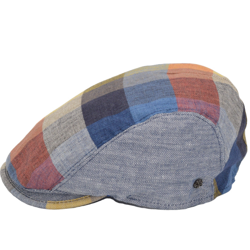 Side view of a colorful patchwork flat cap made from 100% linen. The cap features a vibrant mix of blues, reds, yellows, and greys with a herringbone texture, highlighting the breathable and lightweight qualities of the linen material.