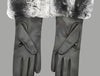 A pair of black women's leather gloves featuring a luxurious gray chinchilla fur trim, displayed on a gray background with both gloves elegantly positioned.